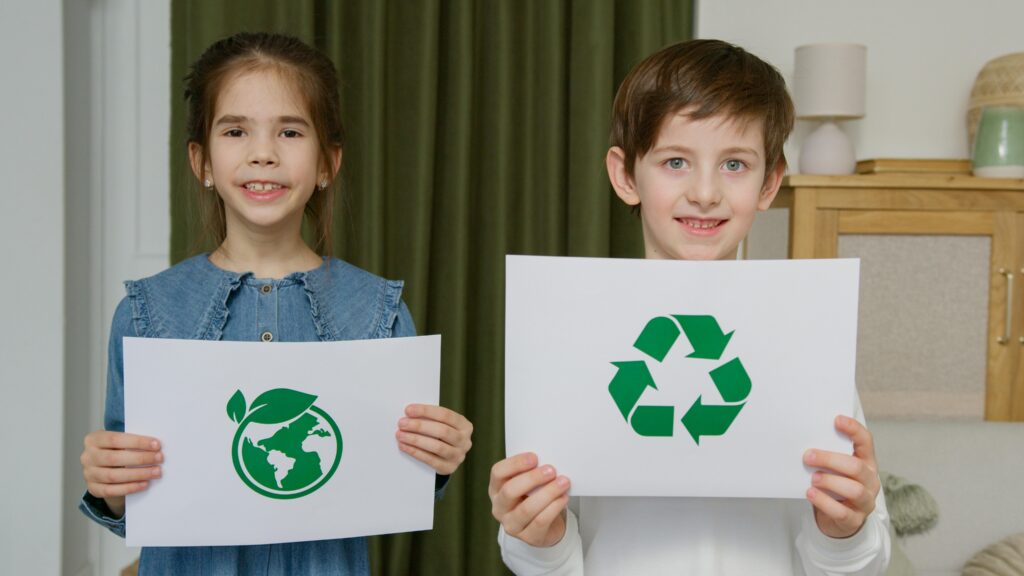 pexels-photo-6990467-6990467 Two children holding eco-friendly signs indoors, promoting sustainability.